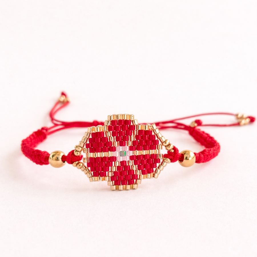 Pulsera flor ROJA artesanal de cuentas Miyuki sobre fondo blanco puro, mostrando el diseño floral central y el cordón rojo. Hecha a mano en Málaga por Joyas Coquetas.