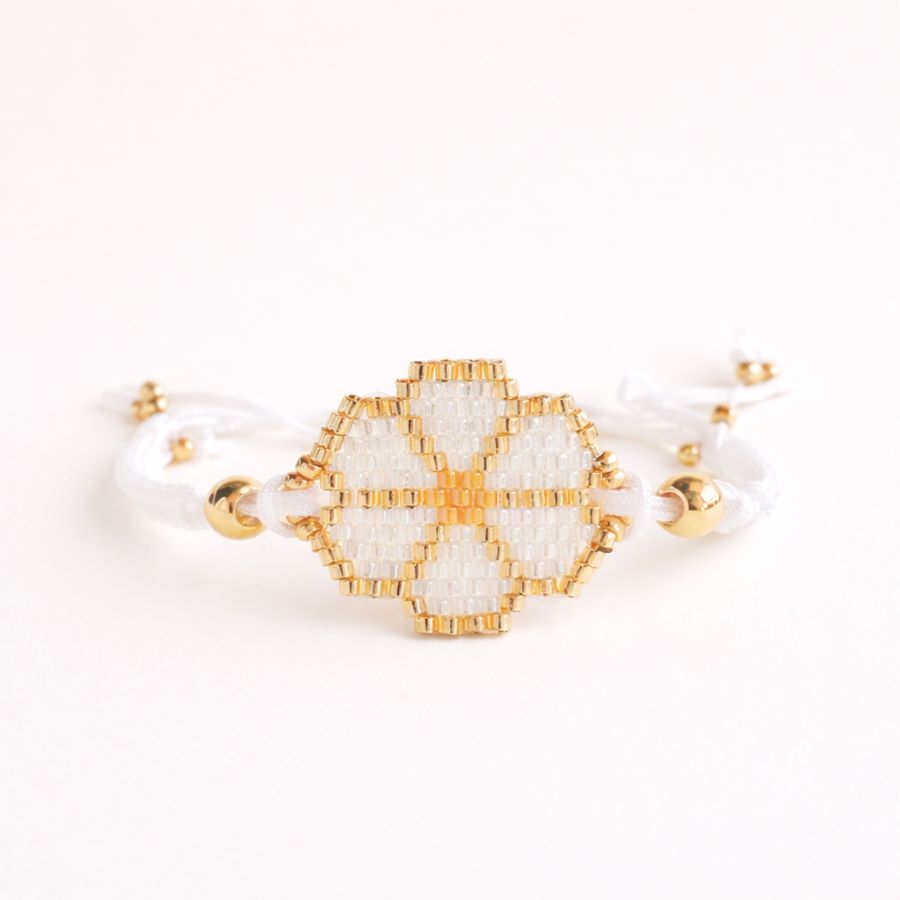 Pulsera flor blanca con Plano frontal limpio de una pulsera artesanal con flor de cuentas Miyuki blancas y bolitas doradas sobre un fondo blanco puro minimalista. Hecha a mano por Joyas Coquetas en Málaga