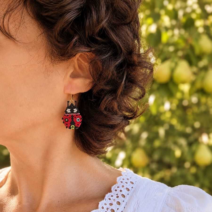 Mujer llevando pendientes mariquita roja artesanales hechos a mano por Joyas Coquetas en Málaga