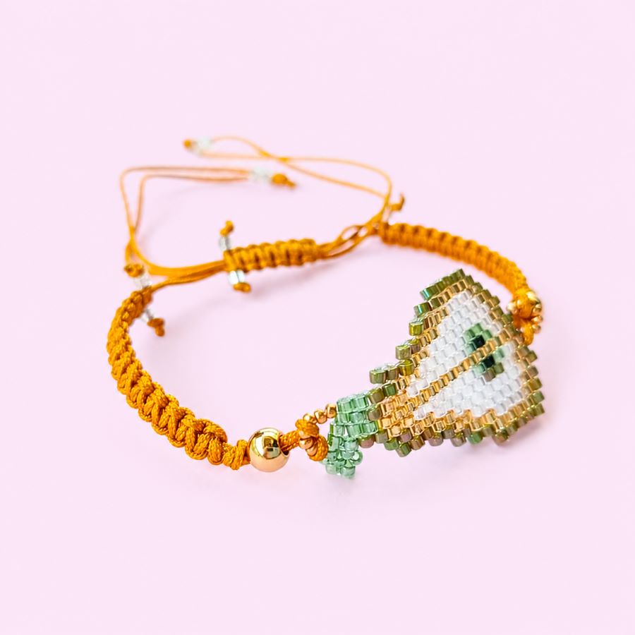 Pulsera Ajustable Pera de Cristal Miyuki: Joyería Artesanal Chic con Macramé Mostaza • Joyas Coquetas Detalle lateral de pulsera artesanal de pera con bolitas doradas de acero inoxidable y macramé. Pulsera hecha a mano en Málaga por Joyas Coquetas.