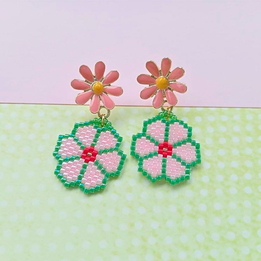 Pendientes margarita rosa artesanales sobre fondo pastel. Hechos a mano por Joyas Coquetas en España.