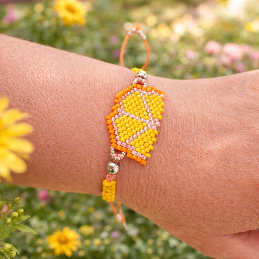 Pulsera frutal naranja puesta en muñeca de mujer. Hecha a mano por Joyas Coquetas en España.