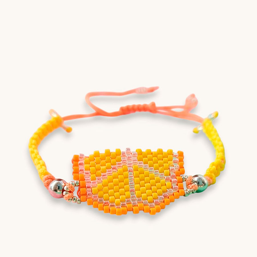 Pulsera frutal naranja, artesanal y hecha a mano con cuentas de cristal Miyuki y cordón macrame. Foto hecha sobre fondo blanco por Joyas Coquetas en Málaga.
