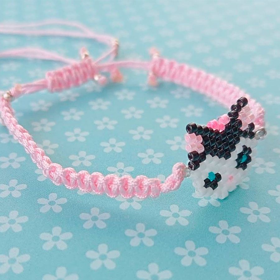 Pulsera Gatita Lazo Rosa • Joyas Coquetas Detalle lateral de Pulsera Gatita Lazo Rosa con cordón de macramé rosa pálido ajustable. Hecha en España por Joyas Coquetas.