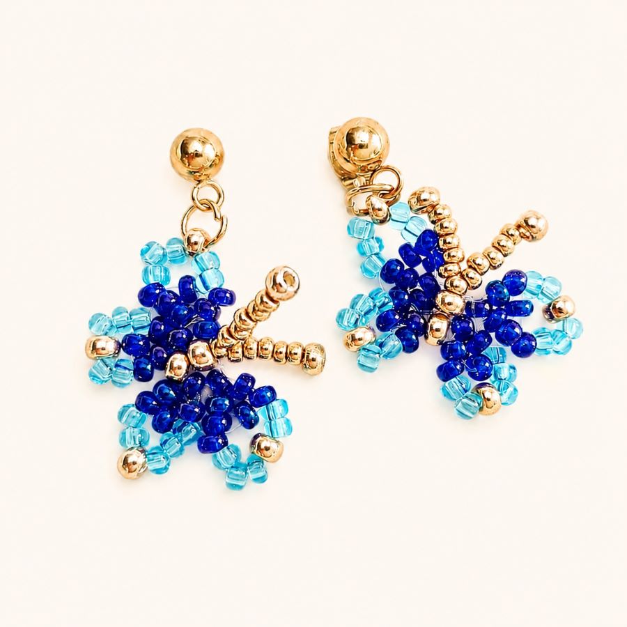 Pendientes mariposas miyuki azules. hechos a mano por Joyas Coquetas en Málaga sobre fondo blanco minimalista.