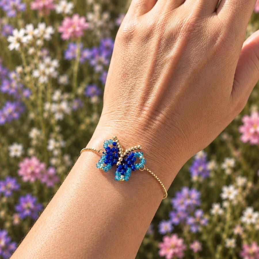 Pulsera mariposa azul hecha a mano en Málaga por Joyas Coquetas puesta en la muñeca con cadena ajustable de acero inoxidable dorado